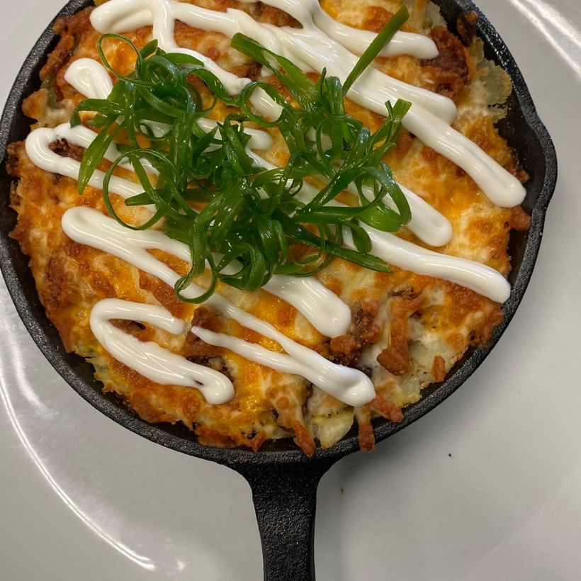 A cast-iron skillet bake finished with cream and spring onion
